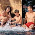 A family delights in the water at a swimming pool, showcasing fun vacation spots in California.