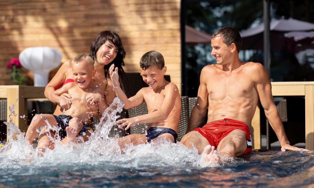 A family delights in the water at a swimming pool, showcasing fun vacation spots in California.