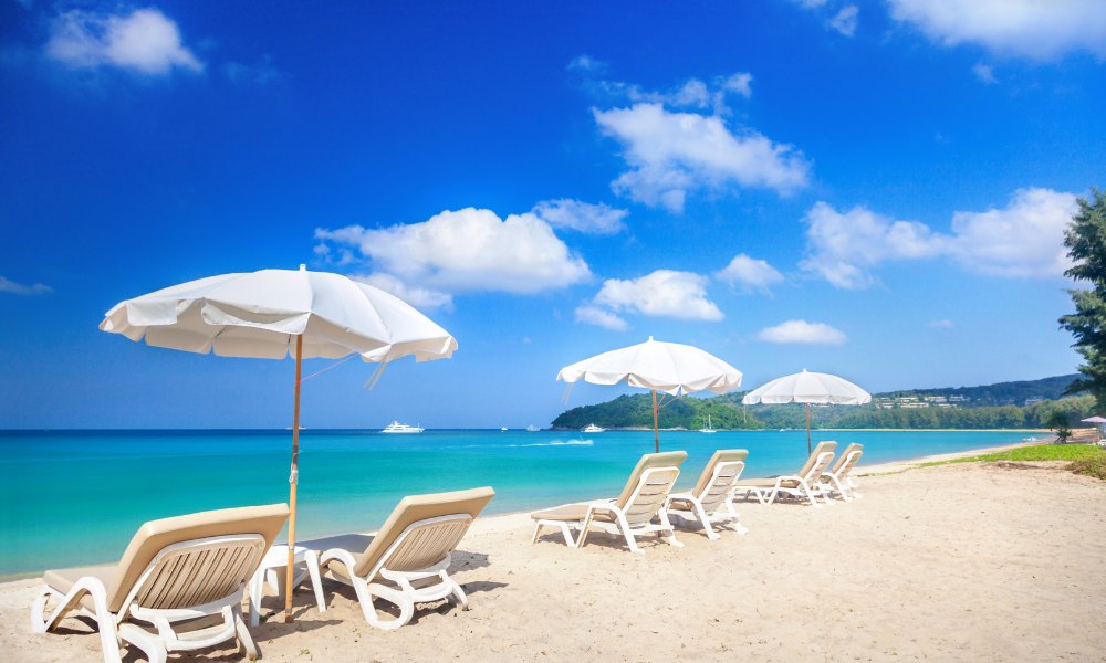 White loungers and umbrellas on a pristine beach with turquoise waters and clear blue skies represent the relaxing atmosphere of vacation islands in Florida.