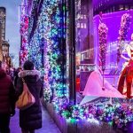 A festive Christmas display in a window as people stroll by, enjoying the holiday decorations and atmosphere.