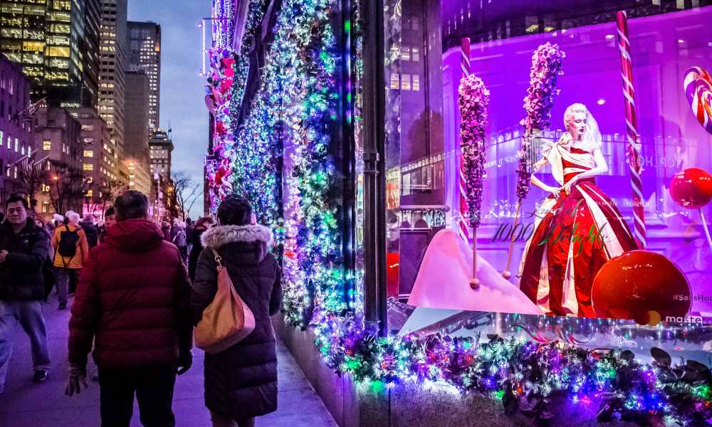 A festive Christmas display in a window as people stroll by, enjoying the holiday decorations and atmosphere.