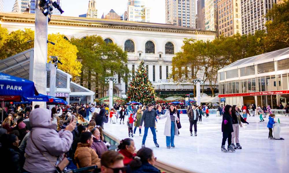 A group of people skating on an ice rink, with a large building visible in the background.