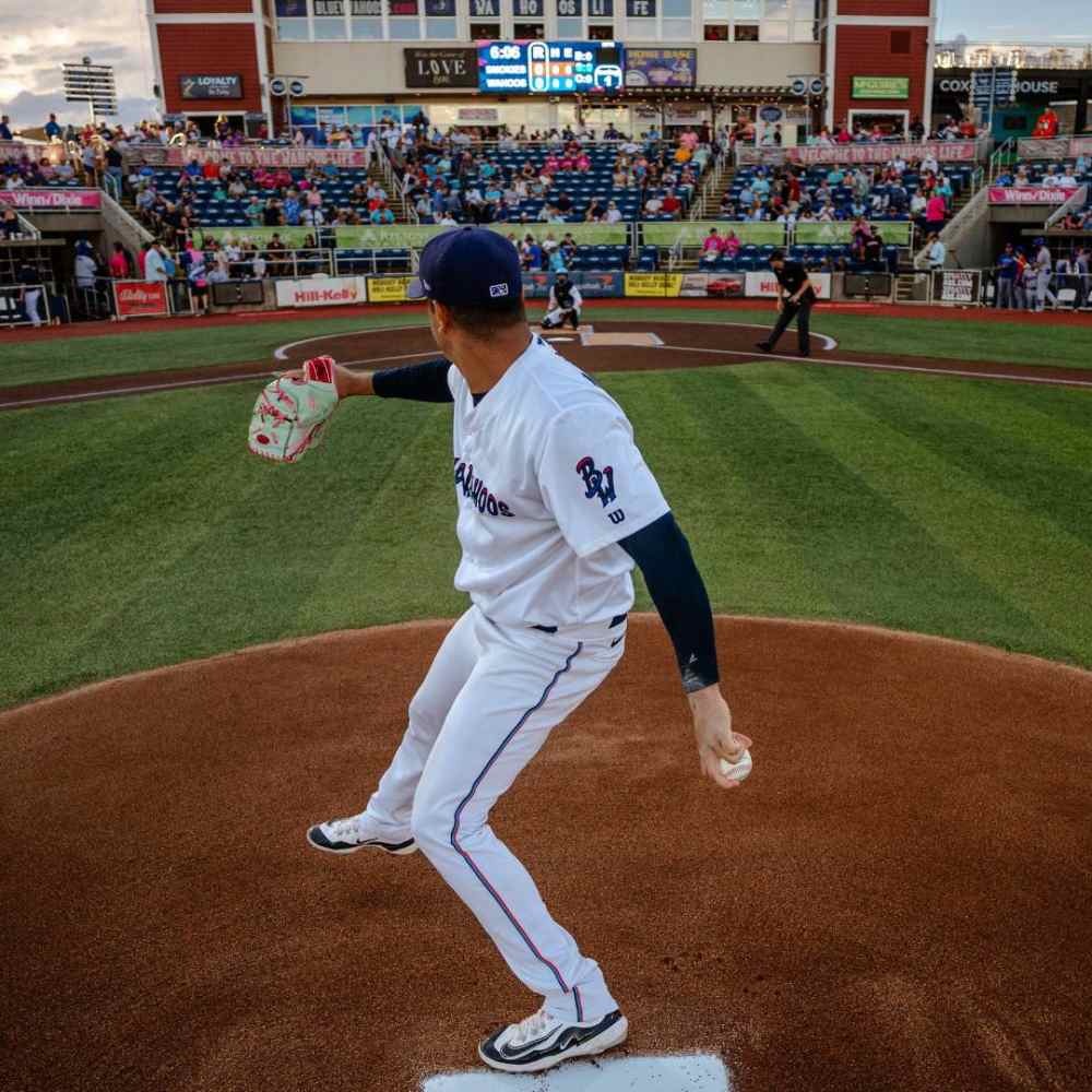 A baseball player in a white uniform stands confidently on the mound at Blue Wahoos Ballpark, ready to pitch.