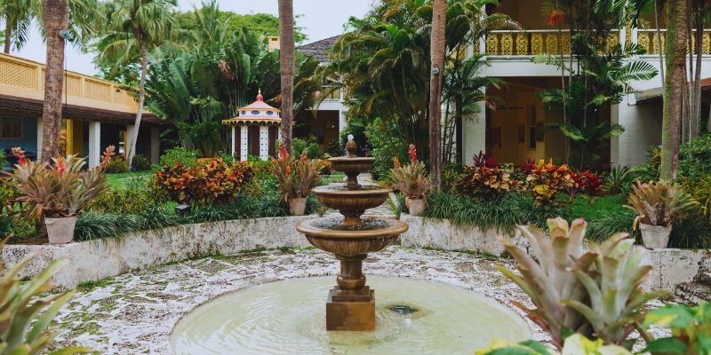 A serene fountain in a courtyard, elegantly framed by lush palm trees, creating a tranquil outdoor oasis.