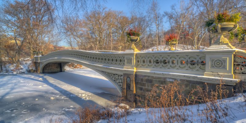 Bow Bridge in New York features a picturesque snow-covered path, enhancing the winter ambiance.