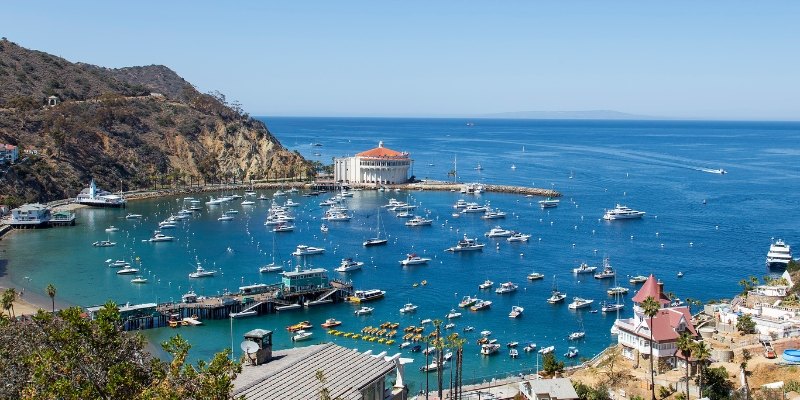 A serene harbor with boats docked, framed by a majestic mountain backdrop on Catalina Island, Southern California.