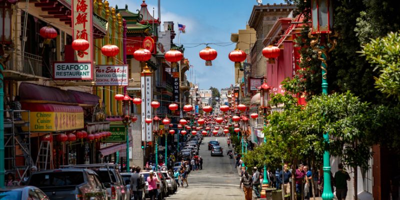 A bustling Chinatown street filled with red lanterns hanging from buildings, showcasing its rich cultural heritage.