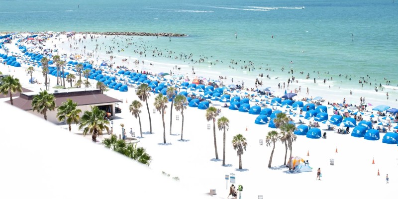 A vibrant beach scene filled with colorful umbrellas and people enjoying the sun and surf.