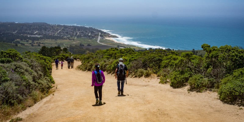 Hikers traverse a scenic trail leading to the ocean along the beautiful California coastline.