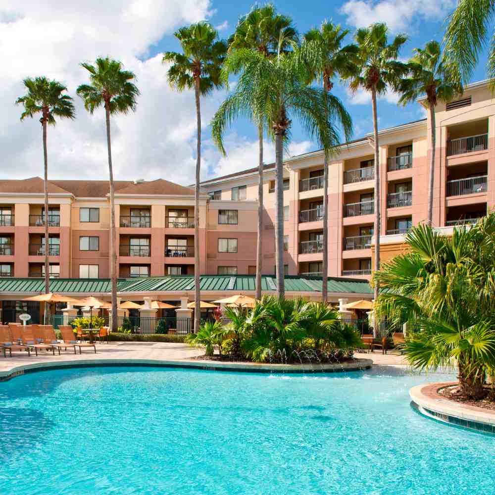 A picturesque view of the courtyard pool at Courtyard by Marriott, framed by vibrant landscaping and sunlit relaxation spots.