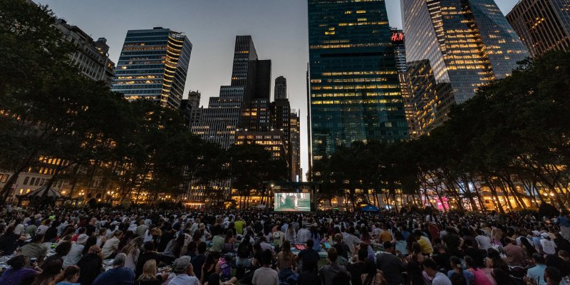 People of all ages enjoy a movie night in Bryant Park, surrounded by the vibrant atmosphere of the city.