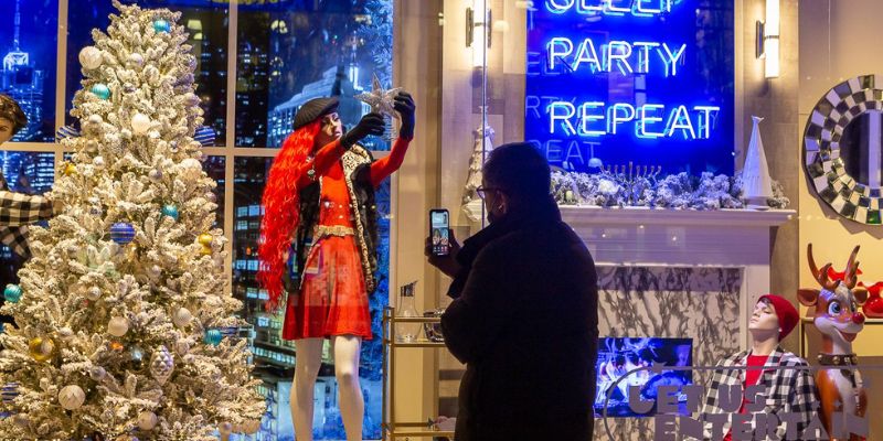 A man captures a photo of a beautifully decorated Christmas tree displayed in a store window.