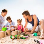 A happy family having fun at the beach, playing with sand and enjoying each other's company on a sunny day.