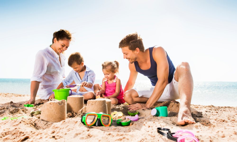 A happy family having fun at the beach, playing with sand and enjoying each other's company on a sunny day.