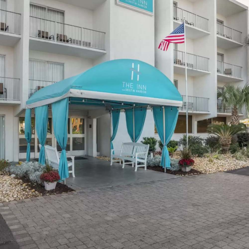 Exterior view of The Inn on Destin Harbor with an American flag and surrounding landscaping.