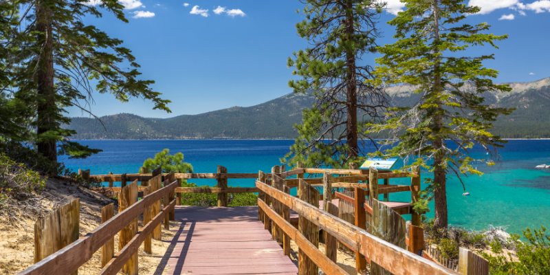 A charming wooden path leads to the serene beach of Lake Tahoe, showcasing its clear, sparkling waters.