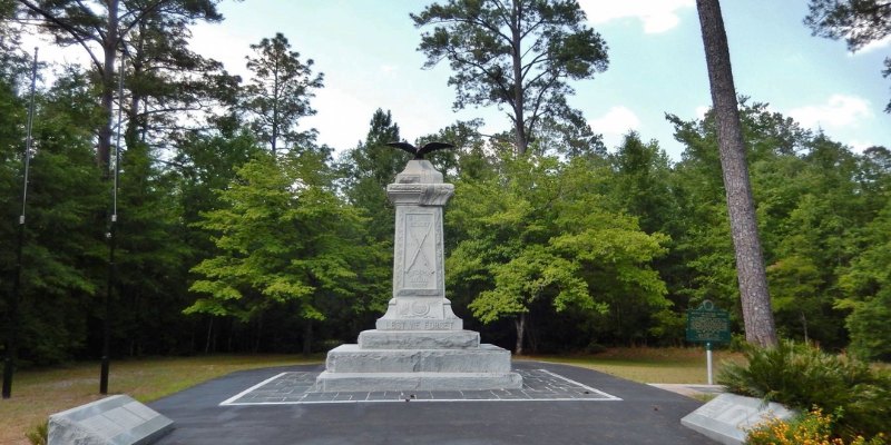 A monument surrounded by verdant trees and a grassy expanse, offering a peaceful and scenic environment.