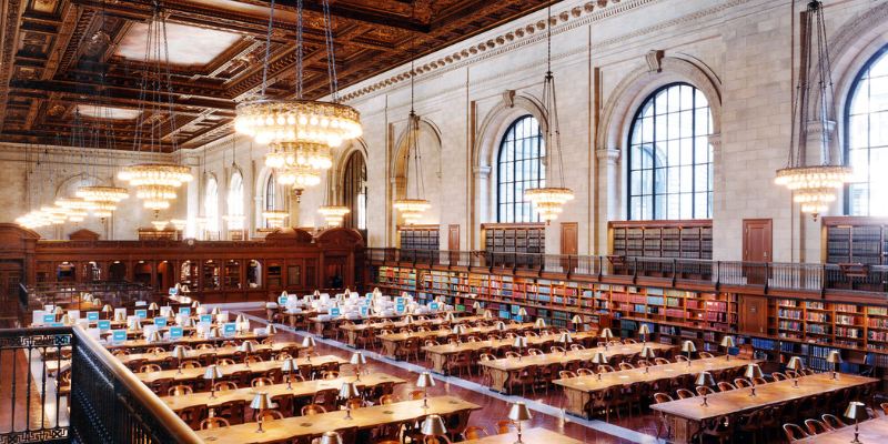 A view of the New York Public Library Reading Room, showcasing its grand architecture and rows of reading tables.