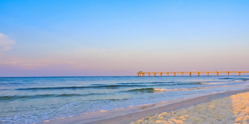 A tranquil beach landscape showcasing a pier and fine sand, perfect for sunbathing and leisurely strolls.