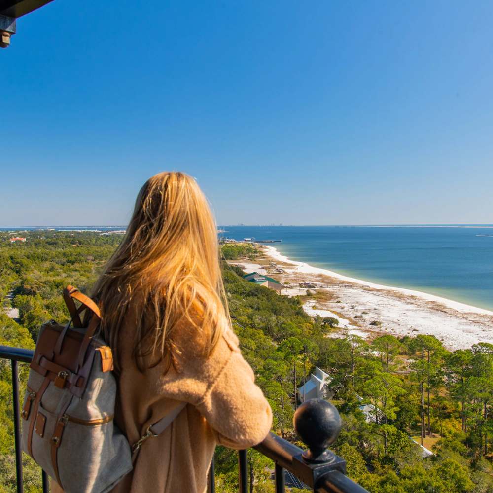 From the top of a tower in Fort Myers, a girl admires the beach, soaking in the stunning ocean scenery.