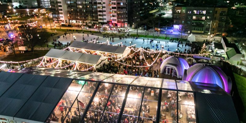 Nighttime aerial perspective of the Roc Holiday Village Winter Festival, featuring a bustling outdoor event filled with lights.