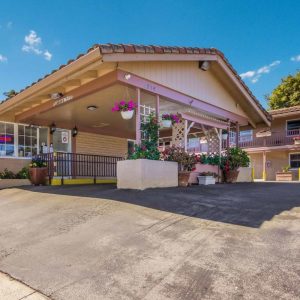 The front entrance of a motel adorned with vibrant flowers and lush plants, creating an inviting atmosphere.