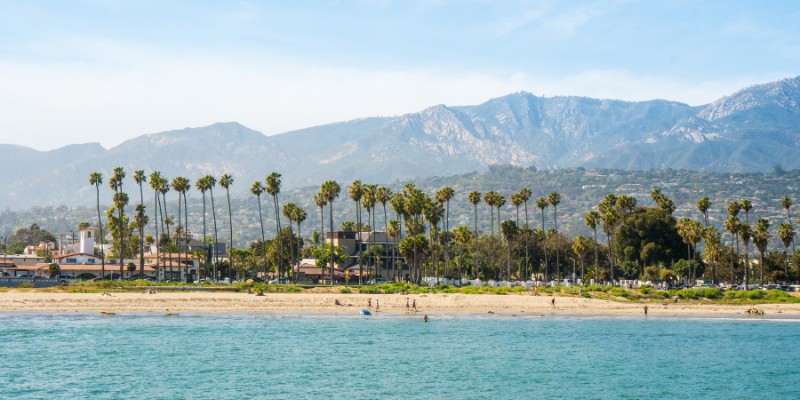 A beautiful Santa Barbara beach with palm trees and majestic mountains in the background.