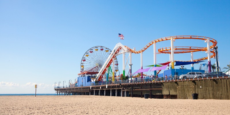 Santa Monica Pier features a colorful roller coaster and ferris wheel, with the beach in the background.