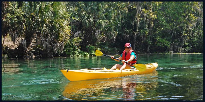 A person kayaking on the clear waters of Silver Springs State Park surrounded by lush greenery in Central Florida.