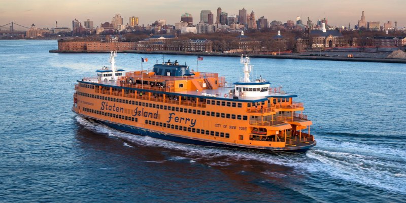 A ferry boat moves through the water, set against the backdrop of a lively urban skyline.