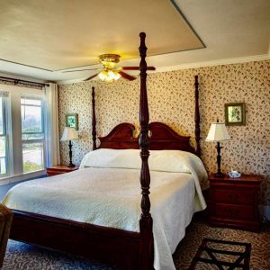 Cozy bedroom featuring a four-poster bed and a bright window, inviting natural light into the space.