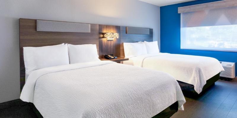 Two neatly arranged beds in a hotel room, complemented by soothing blue walls that enhance the tranquil ambiance.