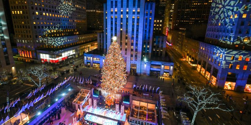 The iconic Rockefeller Center Christmas tree, beautifully lit and decorated, stands tall amidst the bustling holiday atmosphere.