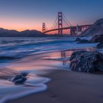 Golden Gate Bridge at sunset with waves on a rocky beach, showcasing California's scenic coastline and ideal travel time for landscapes.