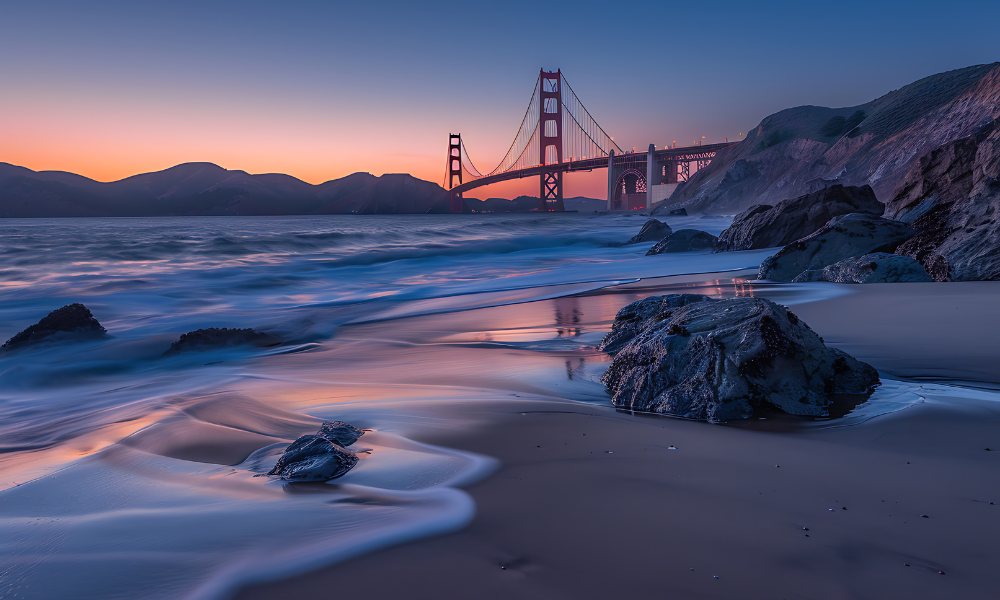 Golden Gate Bridge at sunset with waves on a rocky beach, showcasing California's scenic coastline and ideal travel time for landscapes.