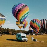 A lively scene of colorful hot air balloons getting ready to take off in a grassy field highlights one of the best things to do in Central Florida.