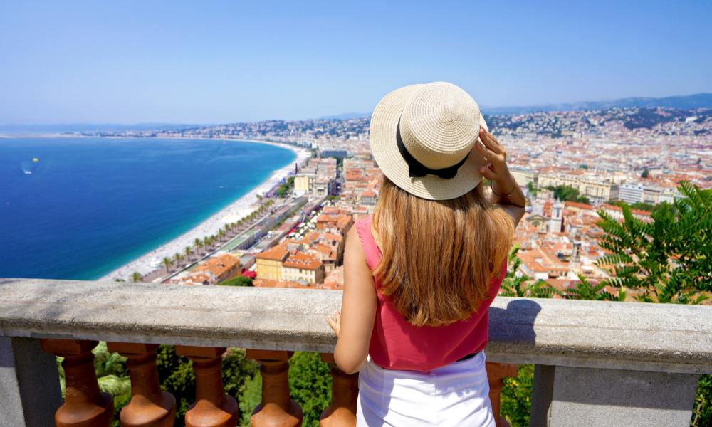 A woman in a hat gazes over the city, capturing the essence of exploring the French Riviera attractions.