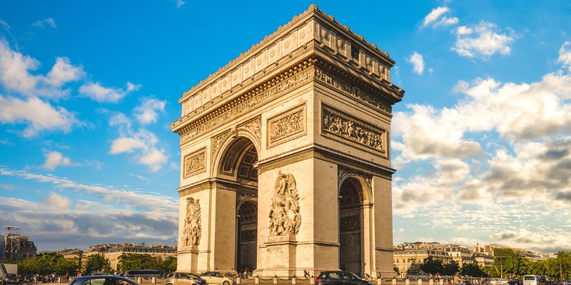 The Arc de Triomphe stands majestically in Paris, France, a symbol of triumph and history against a clear blue sky.