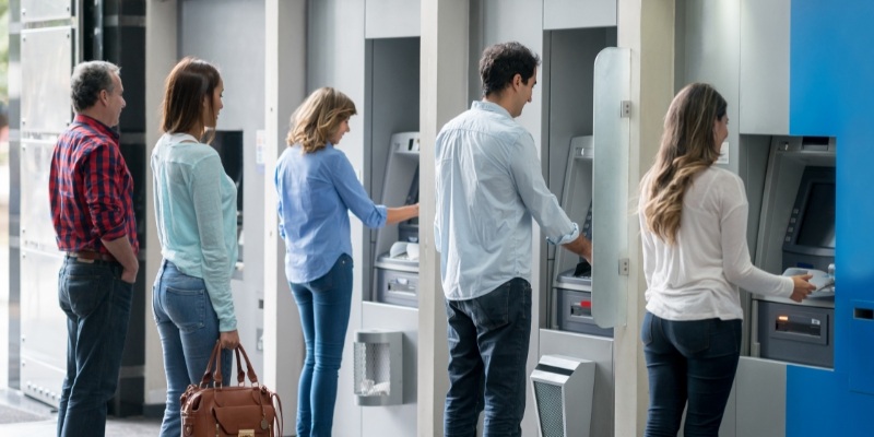 A group of people waiting in line at an ATM, reminding everyone to be cautious while using cash machines.