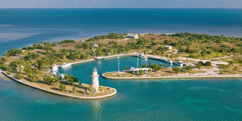 An island scene in Biscayne National Park showcasing a lighthouse with a small boat floating in the calm waters.