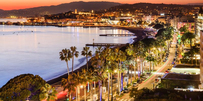 Night view of Boulevard De La Croisette, showcasing the beach and city lights shimmering along the coastline.