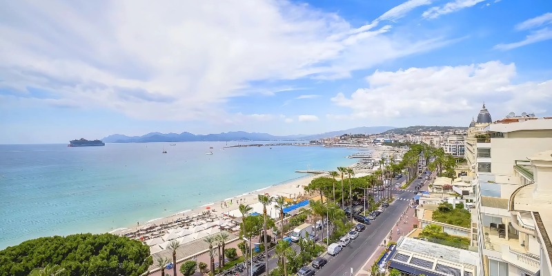 A stunning night scene of Boulevard De La Croisette, with the beach and city illuminated under the starry sky.