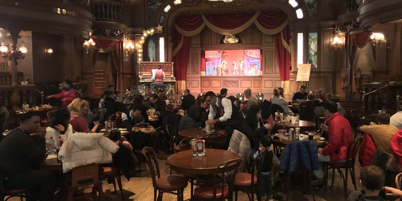 Diners gathered at tables in a lively restaurant at Disneyland Paris, creating a vibrant atmosphere.