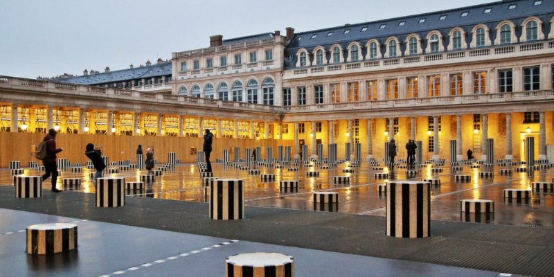 Tourists taking photos by striped poles at Domaine National du Palais-Royal.