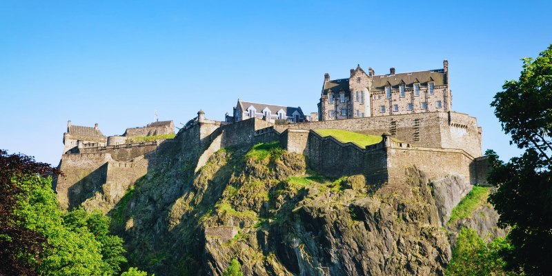 A panoramic view of Edinburgh Castle, perched atop a rocky hill, dominates the skyline of Edinburgh, Scotland, reflecting its rich history.