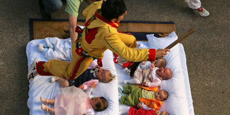 At the El Colacho Baby-Jumping Festival, a man jumps over babies resting on a bed in Castrillo de Murcia.