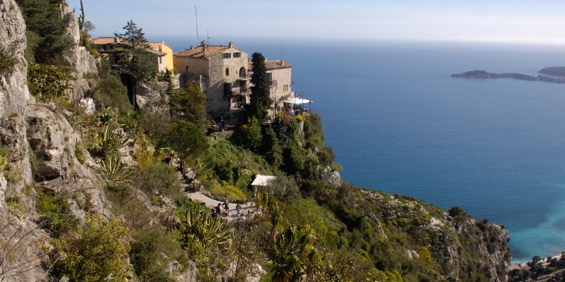 A charming house situated on a cliff, overlooking the serene ocean in Eze, showcasing breathtaking coastal scenery.