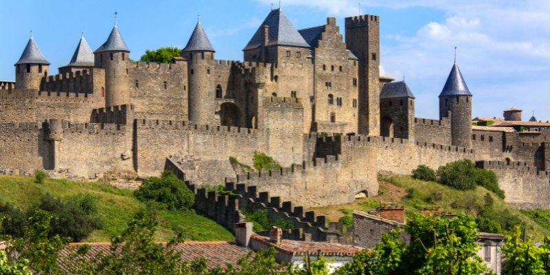 The Castle of Cavaillon in France, framed by colorful autumn leaves, showcases the beauty of fall in Carcassonne.