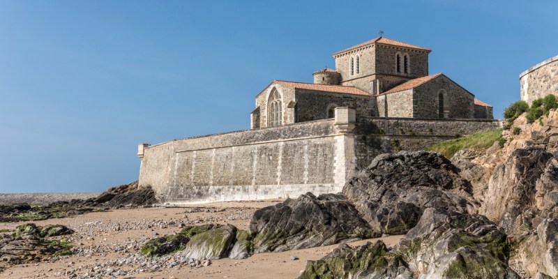 Scenic view of the Church of Saint-Louis-de-la-Salle on the beach, featuring Fort Saint-Nicolas, Marseille, in the distance.