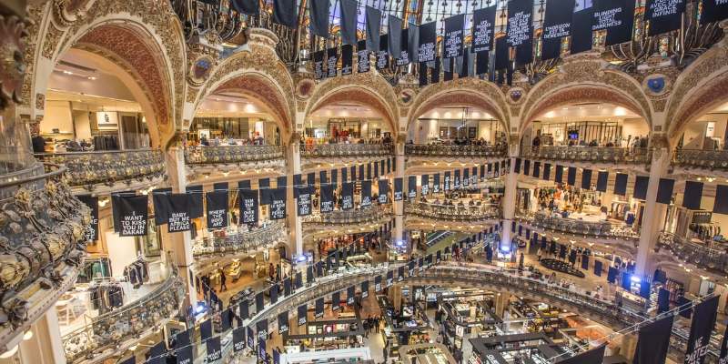 Inside Galeries Lafayette, a vibrant shopping mall teeming with people browsing shops and enjoying their day out.